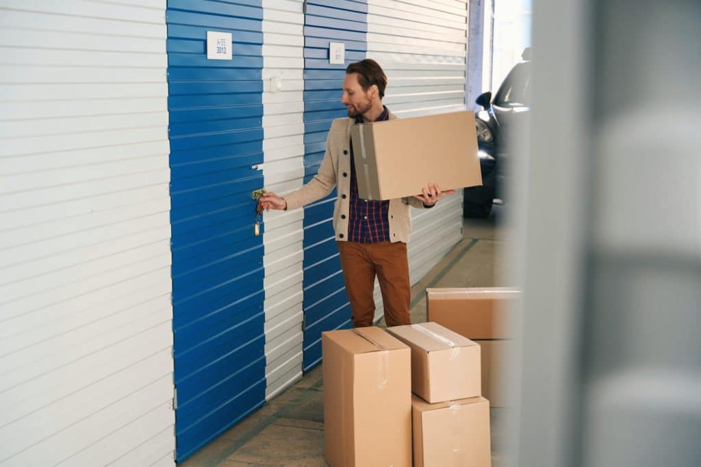 young man with big cardboard boxes in self storage unit